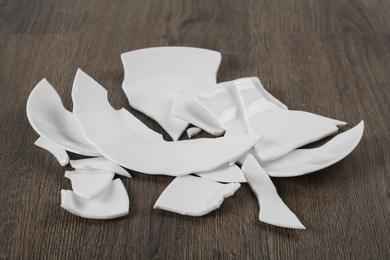 Photo of Pieces of broken ceramic plate on wooden floor