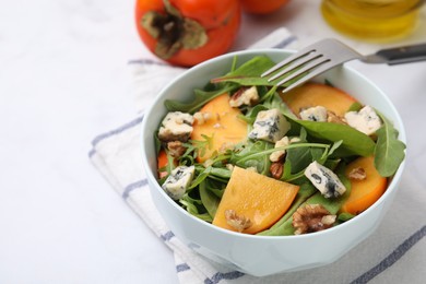 Photo of Tasty salad with persimmon, blue cheese and walnuts served on white table, closeup. Space for text