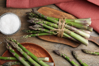 Photo of Fresh raw asparagus on wooden table, flat lay