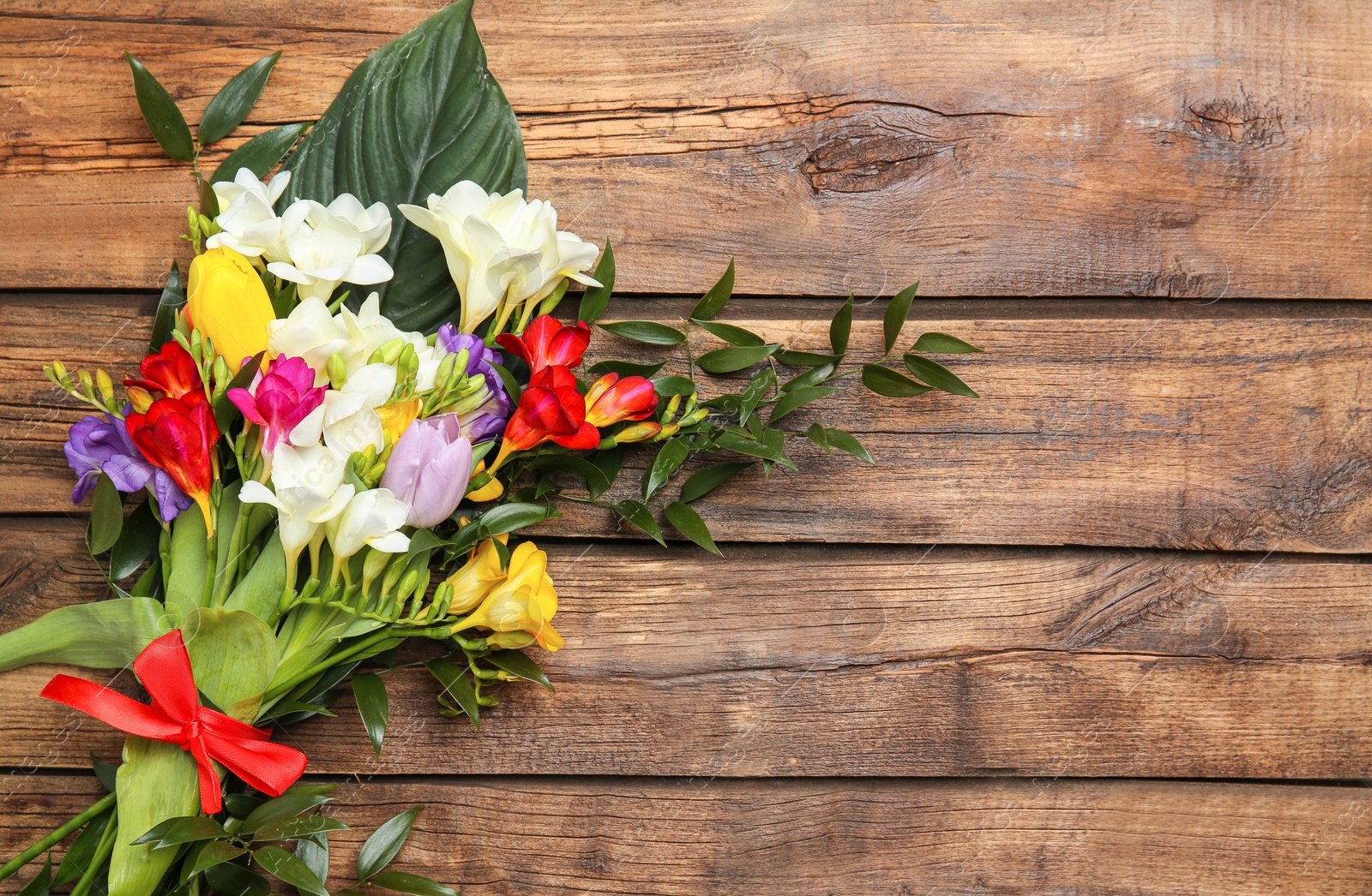 Photo of Beautiful freesia bouquet on wooden background