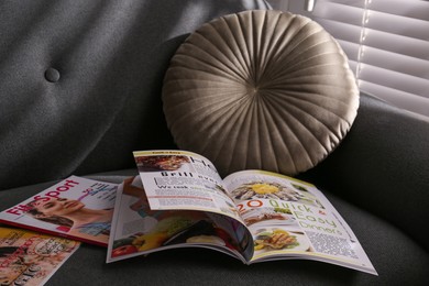 Different lifestyle magazines on comfortable sofa indoors