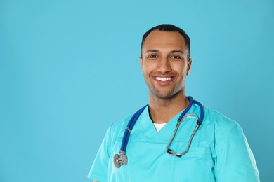 Photo of Doctor or medical assistant (male nurse) with stethoscope on turquoise background. Space for text