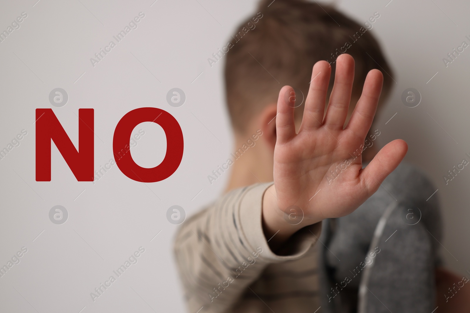 Image of No child abuse. Boy making stop gesture on light background, selective focus