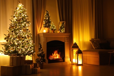 Photo of Stylish living room interior with beautiful fireplace, Christmas tree and other decorations at night