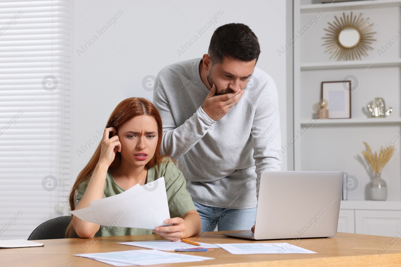 Photo of Emotional couple doing taxes at table in room