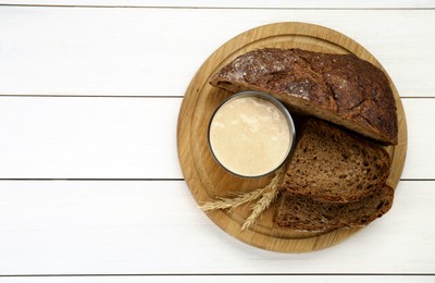 Photo of Freshly baked bread, sourdough and spikes on white wooden table, top view. Space for text