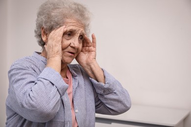 Photo of Senior woman with headache at home. Space for text