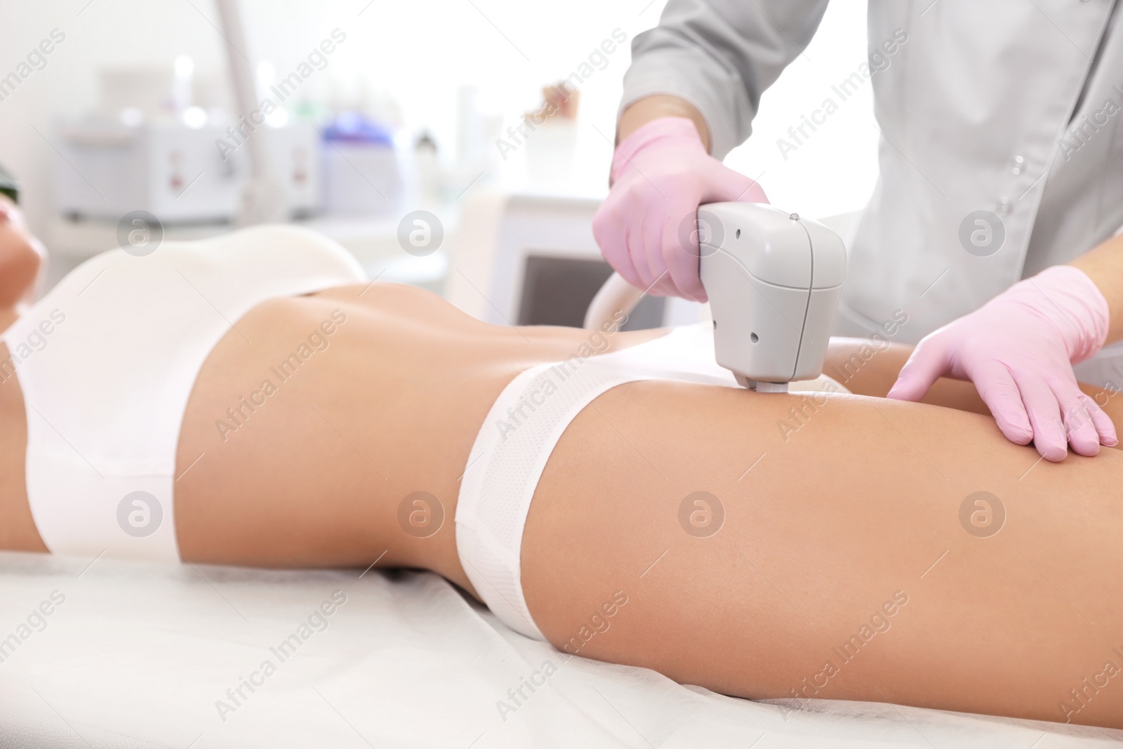 Photo of Young woman undergoing laser epilation procedure in beauty salon, closeup