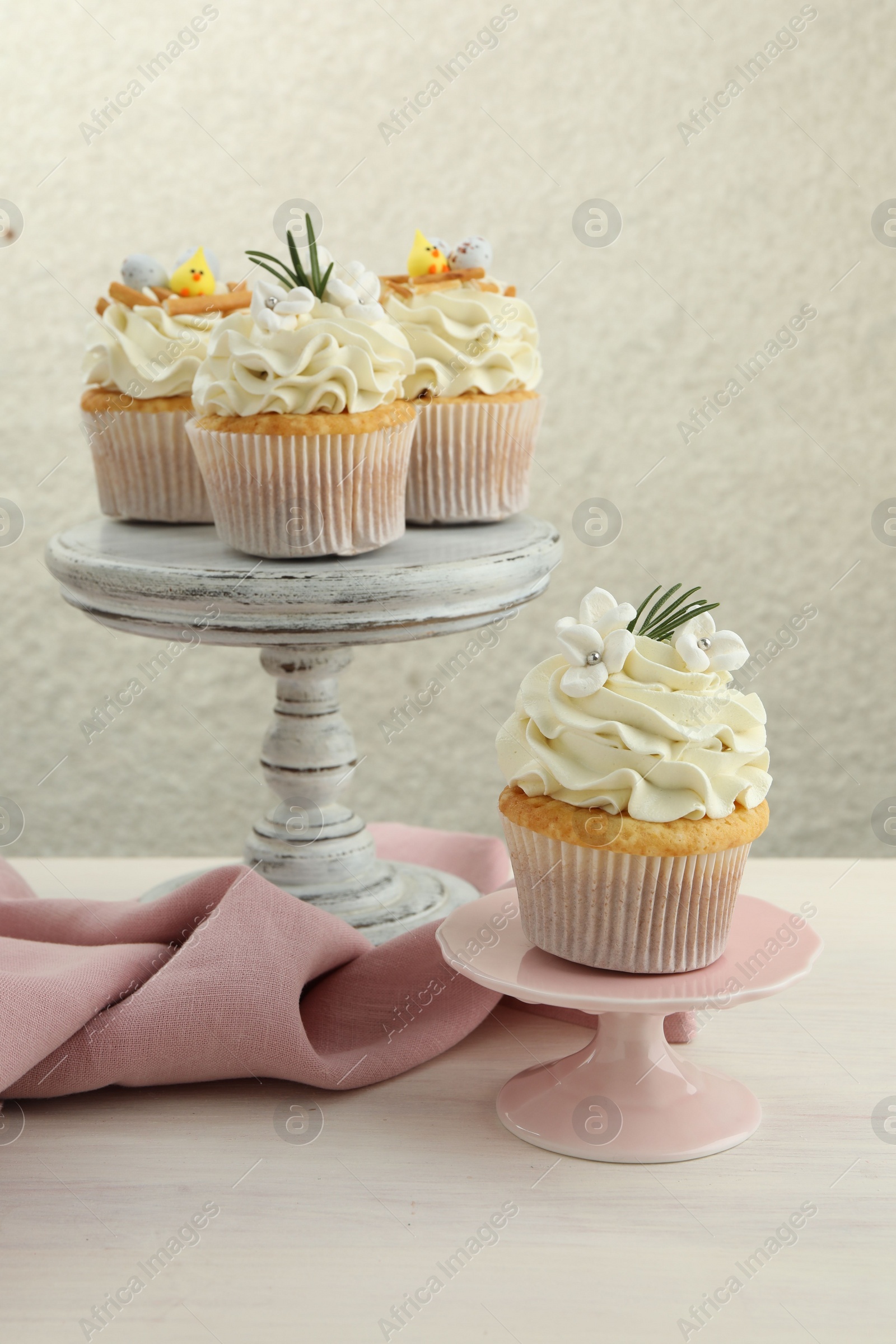 Photo of Tasty Easter cupcakes with vanilla cream on light wooden table