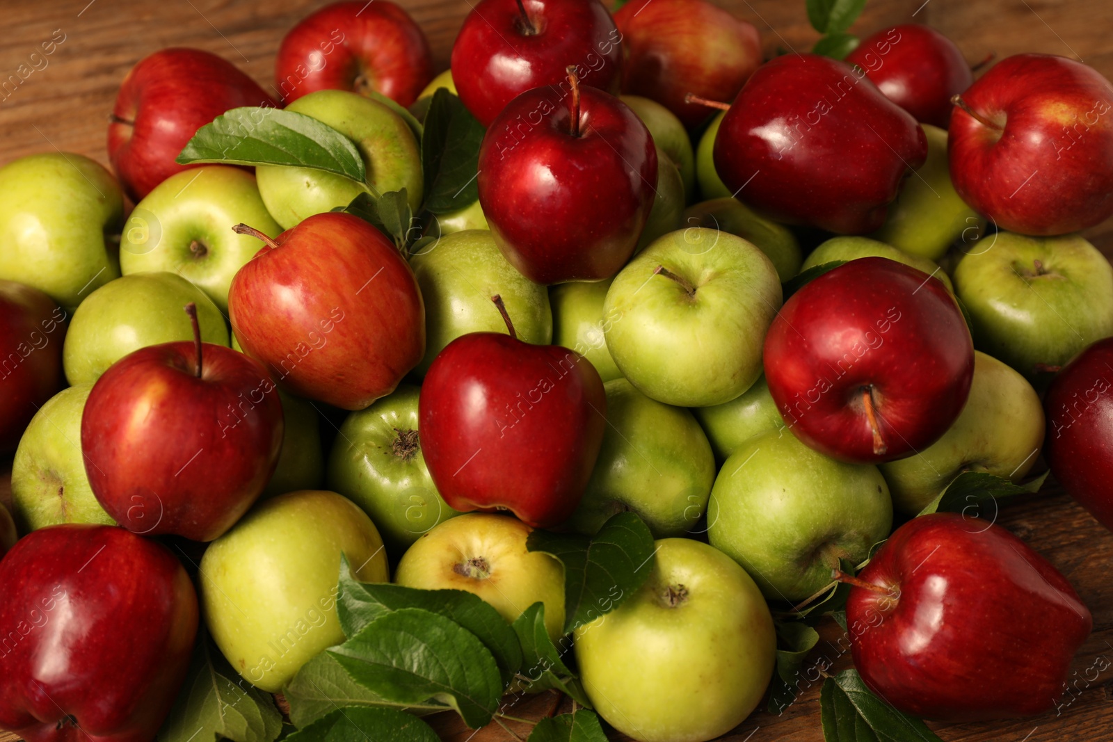 Photo of Fresh ripe apples with leaves on wooden table