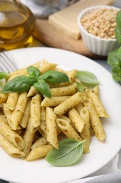 Delicious pasta with pesto sauce and basil on table, closeup