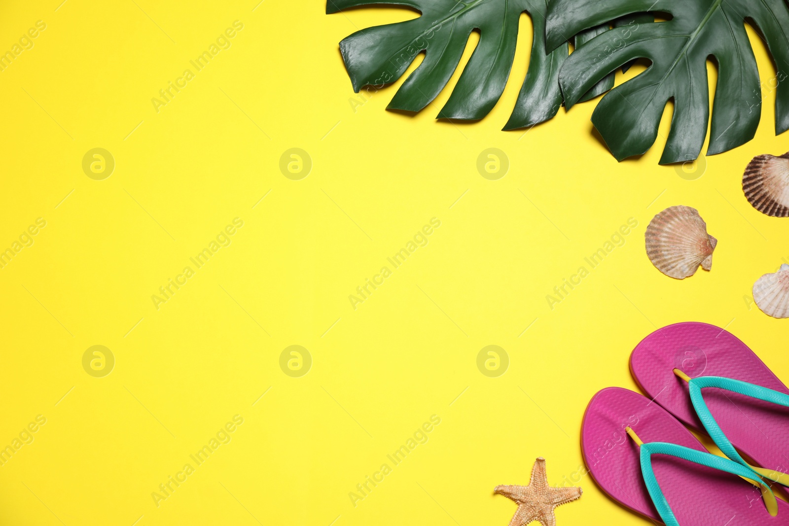 Photo of Beach accessories and leaves on yellow background, flat lay. Space for text