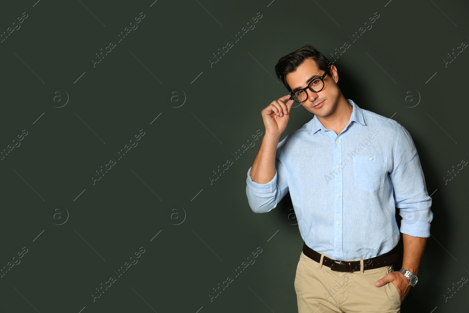 Photo of Handsome young man in stylish clothes with glasses on dark background. Space for text