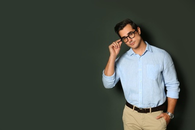 Handsome young man in stylish clothes with glasses on dark background. Space for text