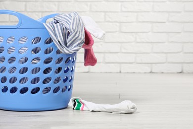 Photo of Laundry basket with clothes near white brick wall. Space for text