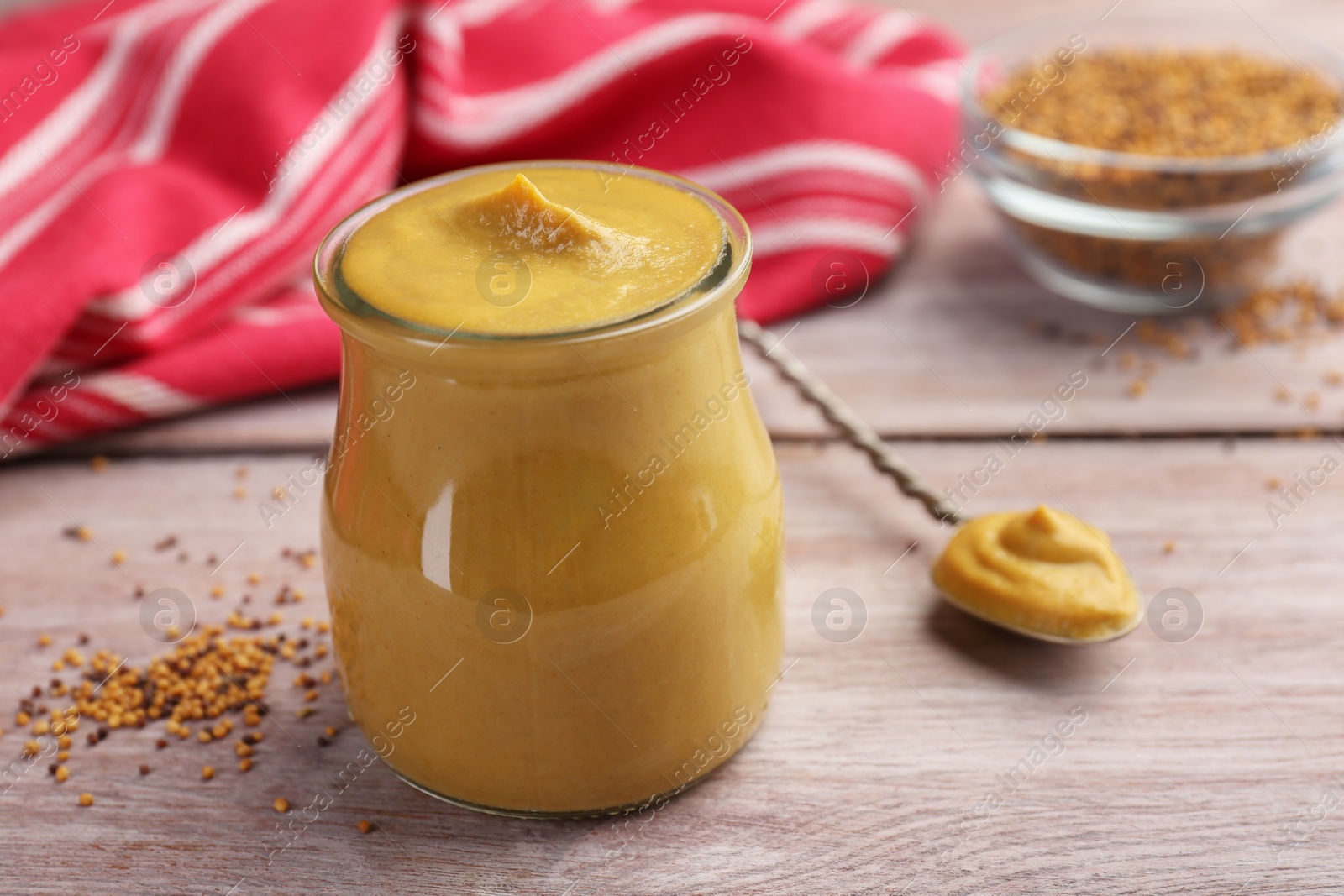 Photo of Tasty mustard sauce in jar on wooden table, closeup