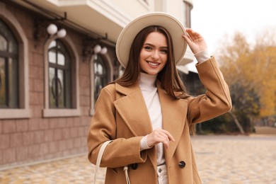 Photo of Beautiful young woman wearing stylish autumn clothes on city street