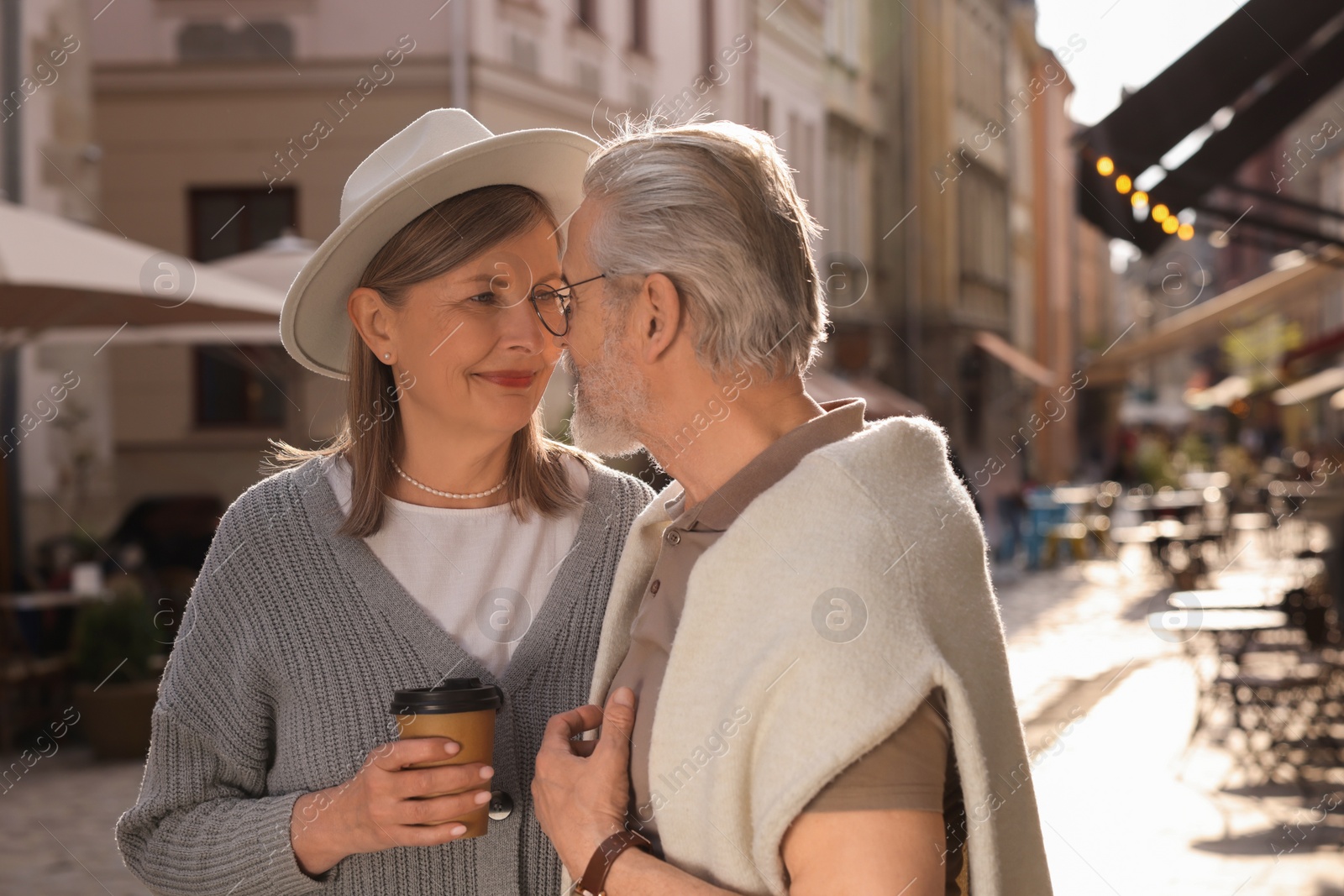 Photo of Affectionate senior couple with coffee walking outdoors, space for text