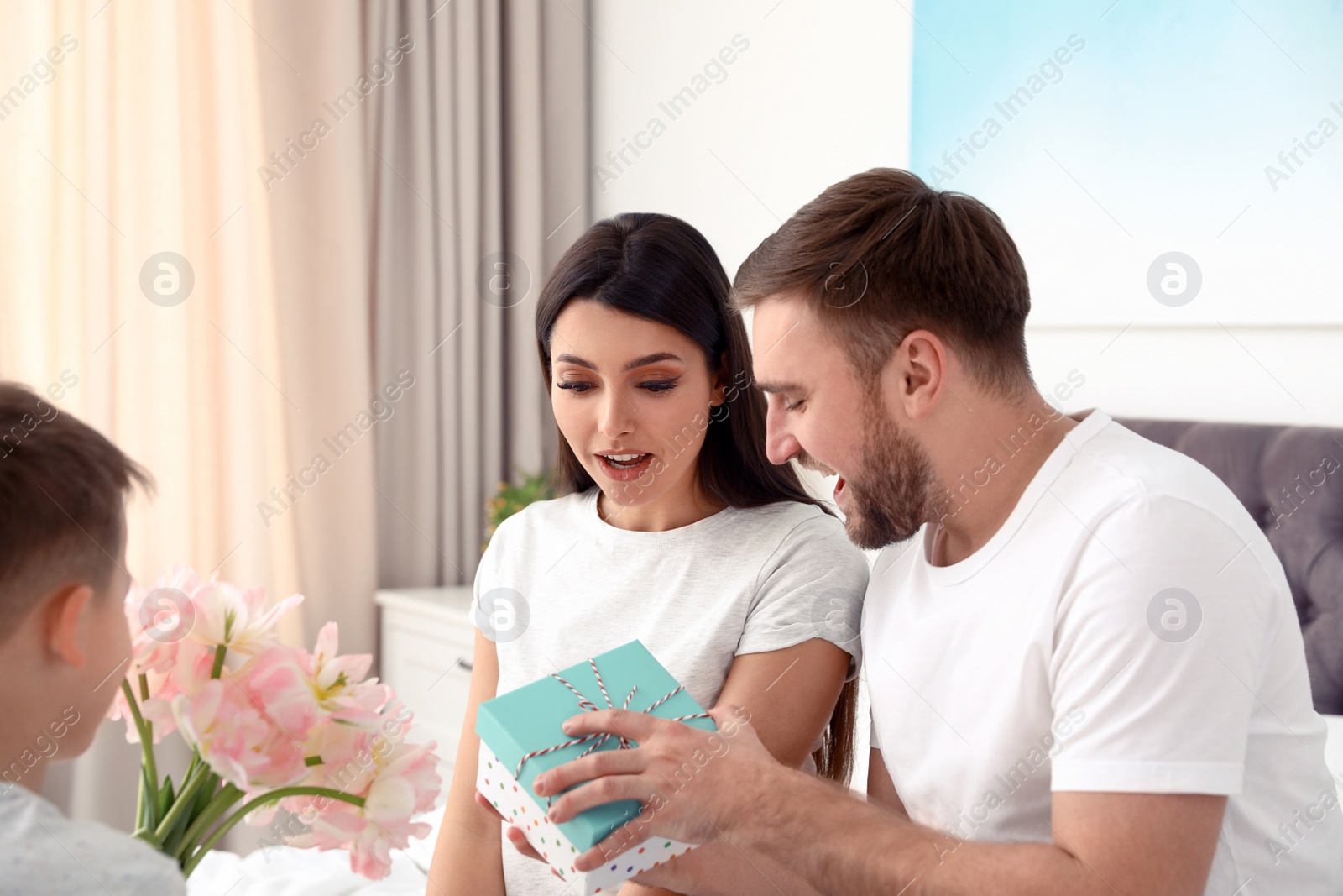 Photo of Father and son congratulating mom in bedroom. Happy Mother's Day