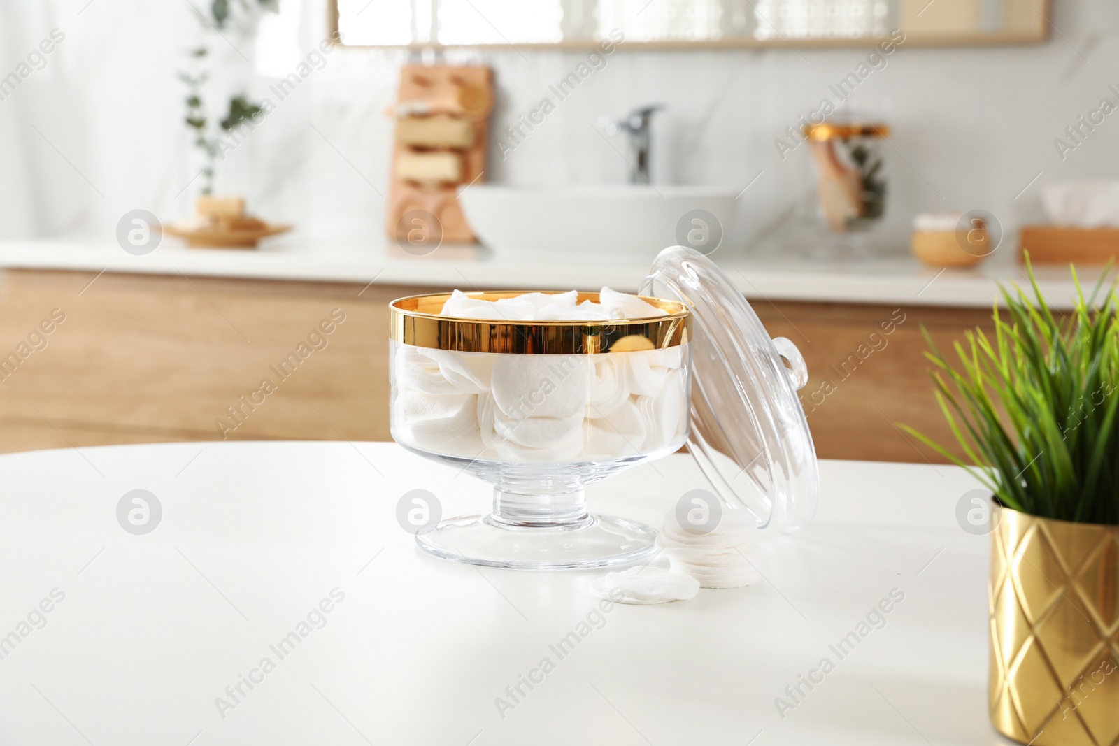 Photo of Jar with cotton pads on table in bathroom