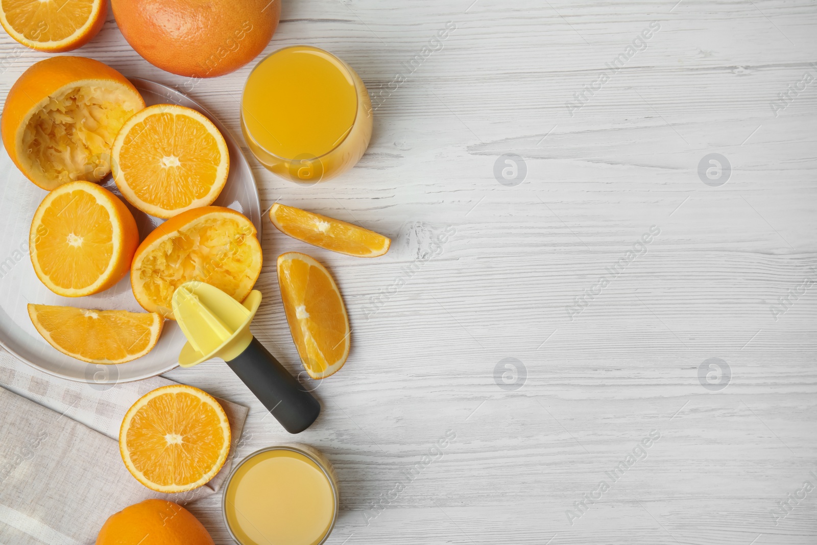 Photo of Fresh oranges, reamer and juice on white wooden table, flat lay. Space for text