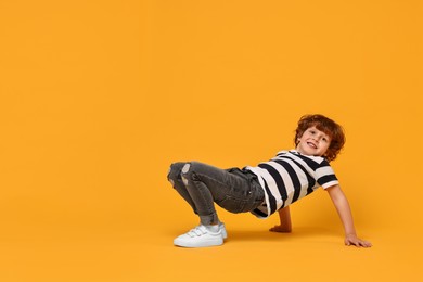 Photo of Happy little boy dancing on yellow background. Space for text