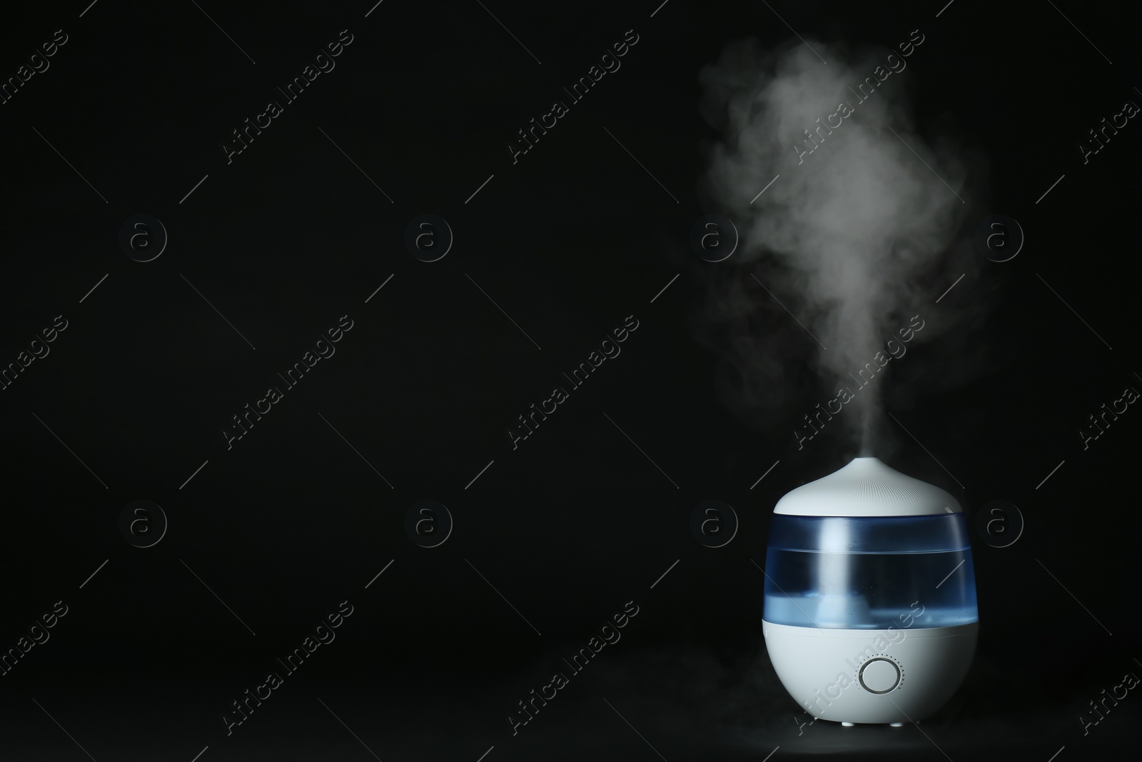 Photo of Modern air humidifier on black background. Space for text