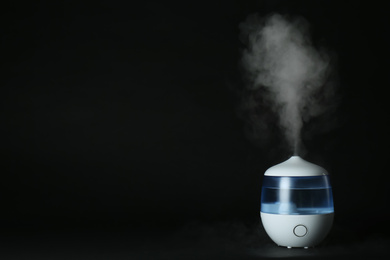 Photo of Modern air humidifier on black background. Space for text