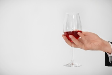 Photo of Man holding glass of wine on light background