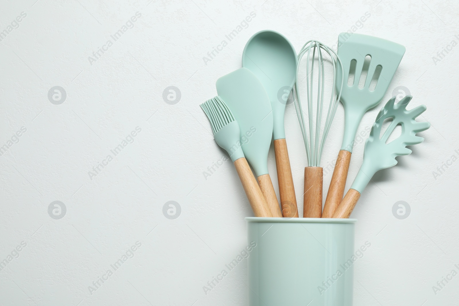 Photo of Set of kitchen utensils in holder on white table, top view. Space for text