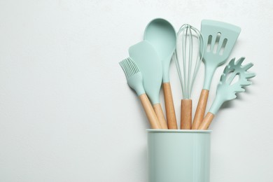 Photo of Set of kitchen utensils in holder on white table, top view. Space for text