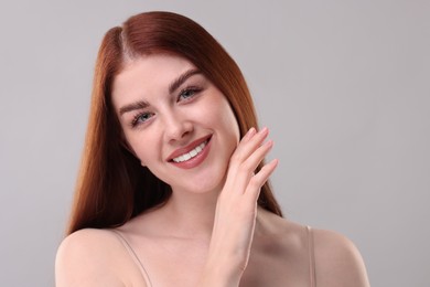 Portrait of smiling woman on grey background, closeup