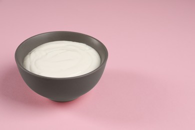 Photo of Bowl of tasty yogurt on pink background, space for text