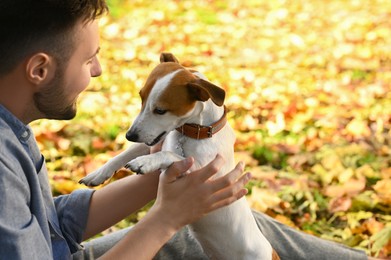 Man with adorable Jack Russell Terrier in autumn park, space for text. Dog walking