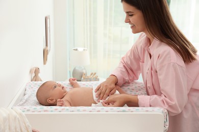 Photo of Mother changing her baby's diaper on table at home