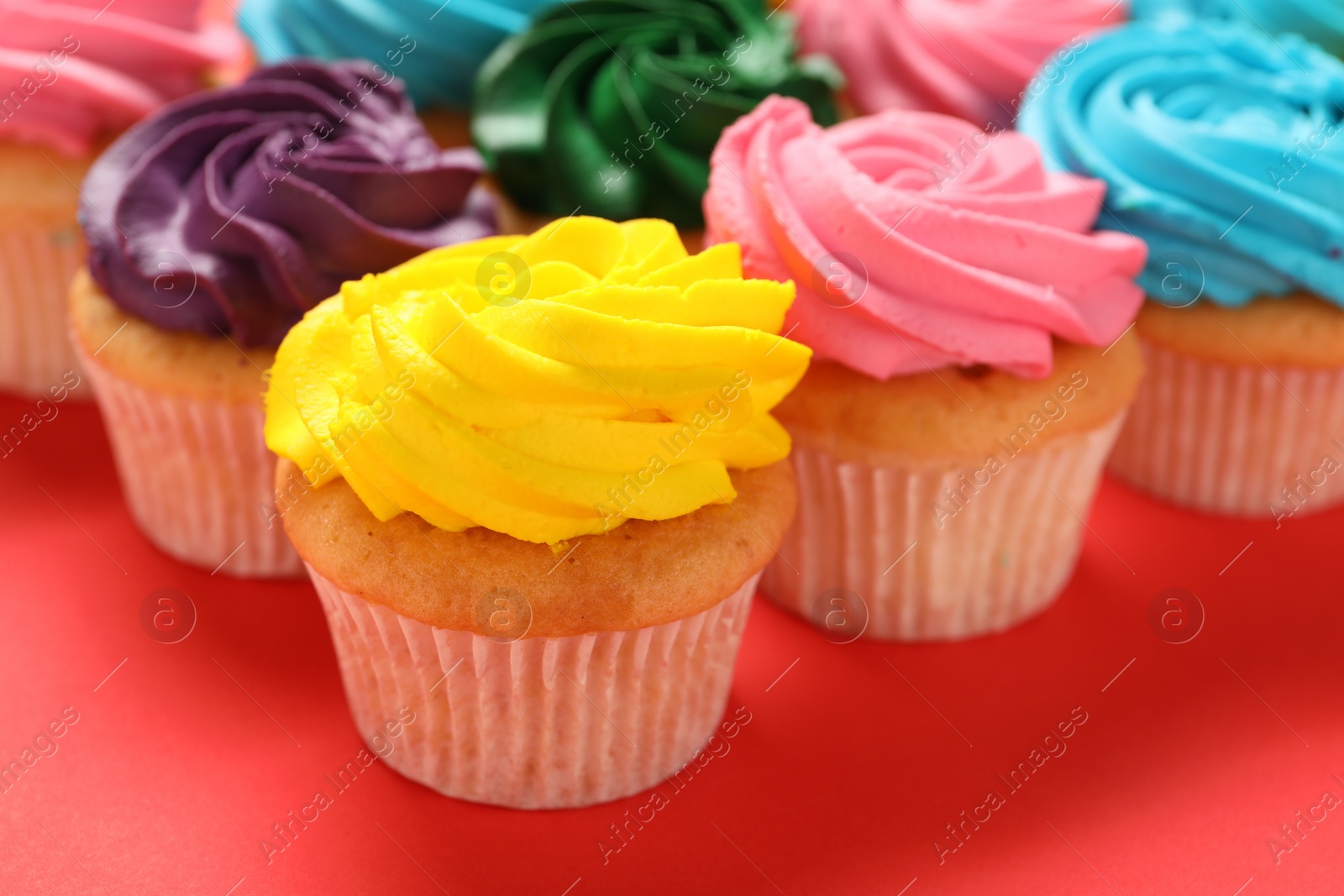 Photo of Delicious cupcakes with bright cream on red background, closeup