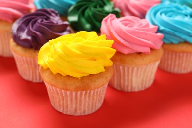 Delicious cupcakes with bright cream on red background, closeup