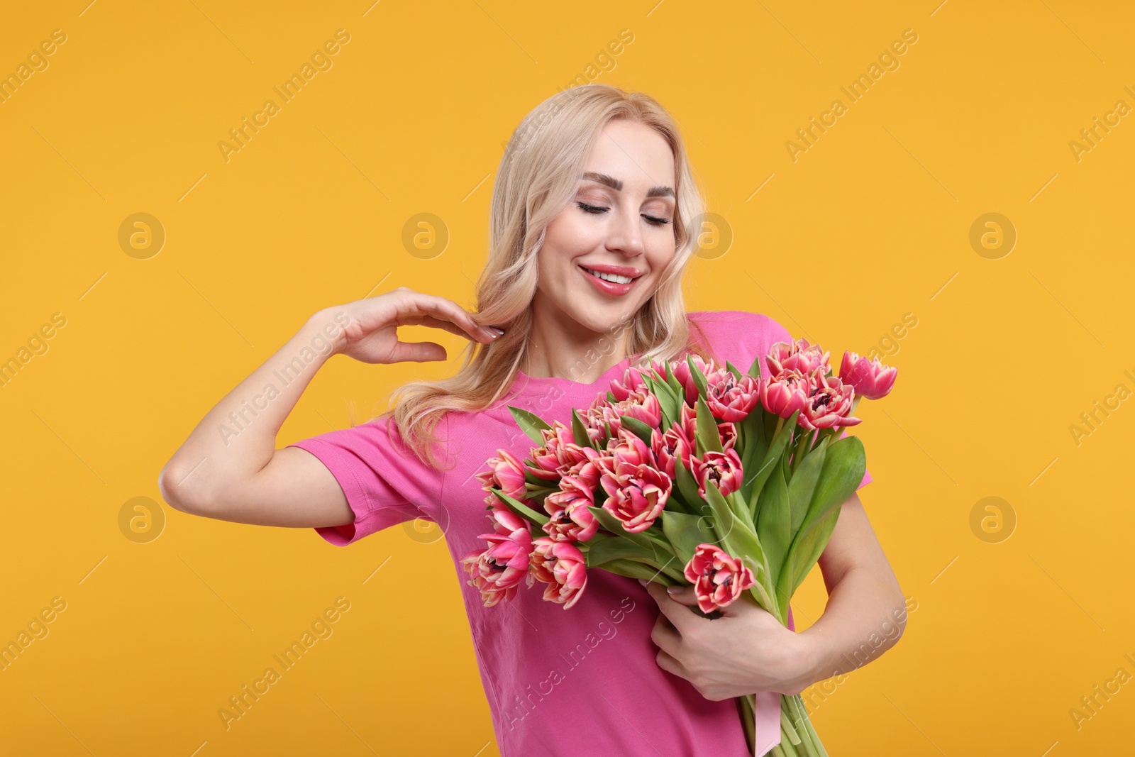 Photo of Happy young woman with beautiful bouquet on orange background