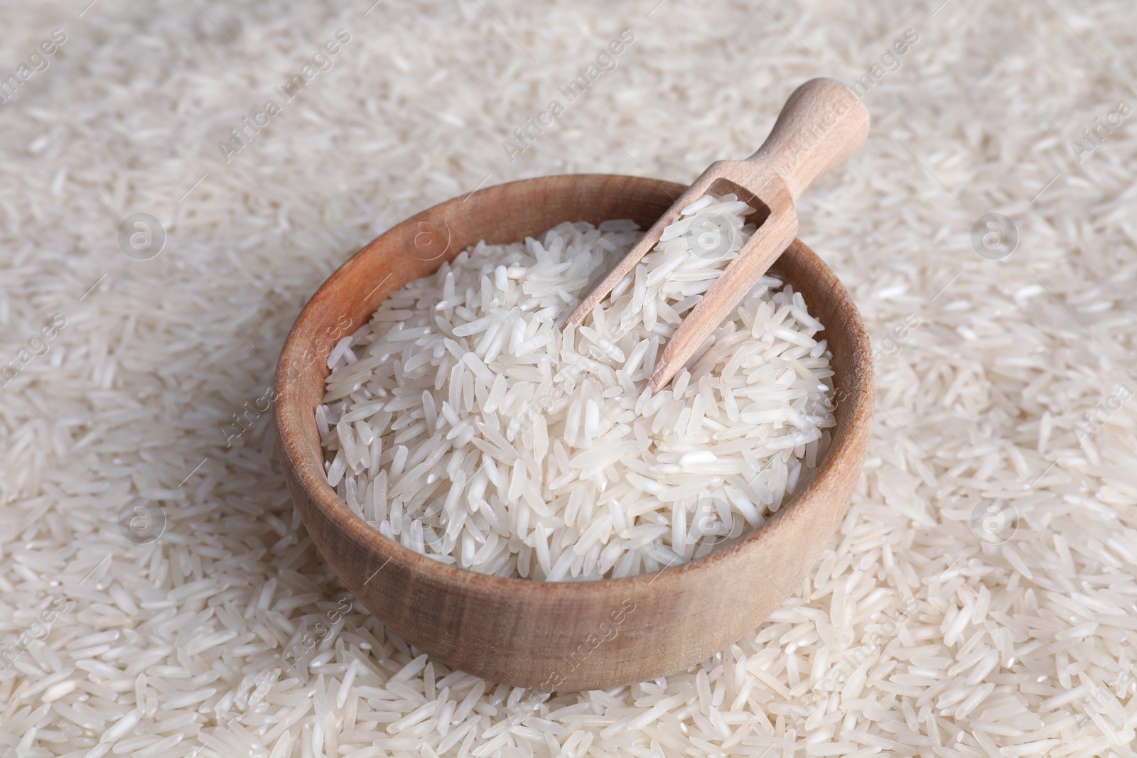 Photo of Raw basmati rice, bowl and scoop as background, closeup