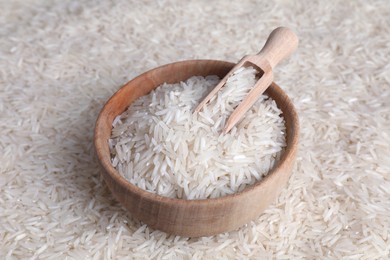 Raw basmati rice, bowl and scoop as background, closeup