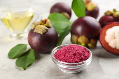 Purple mangosteen powder and fruits on light grey table