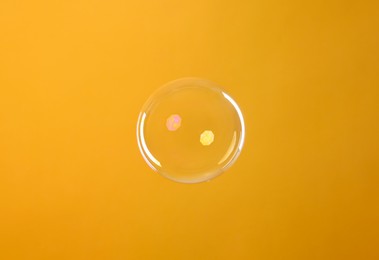 Photo of One beautiful soap bubble on orange background