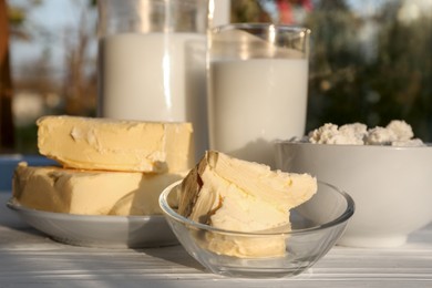 Photo of Tasty homemade butter and dairy products on white wooden windowsill, closeup