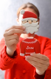 Photo of Woman holding delicious homemade Christmas cookies on grey background, closeup