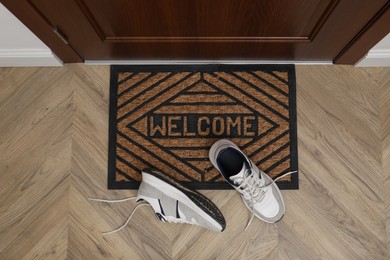 Photo of Stylish shoes near door mat in hall, top view