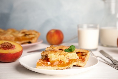 Photo of Piece of delicious fresh peach pie served on white wooden table, closeup