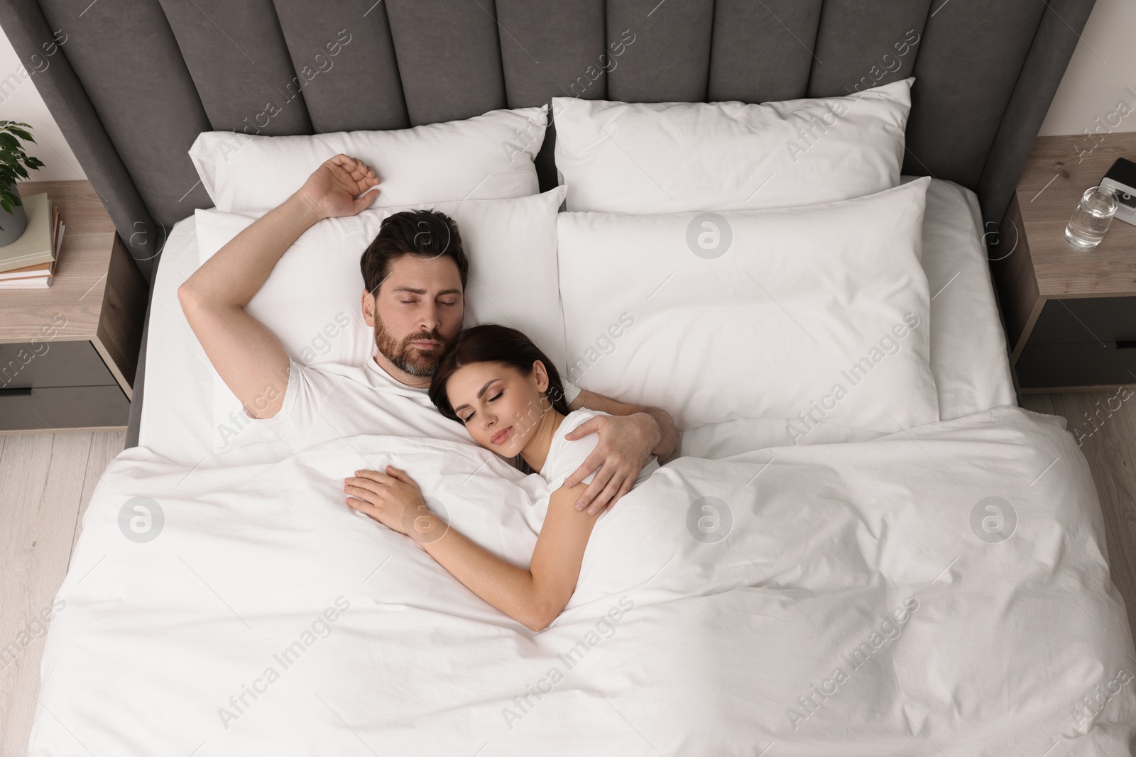 Photo of Lovely couple sleeping together in bed at home, top view