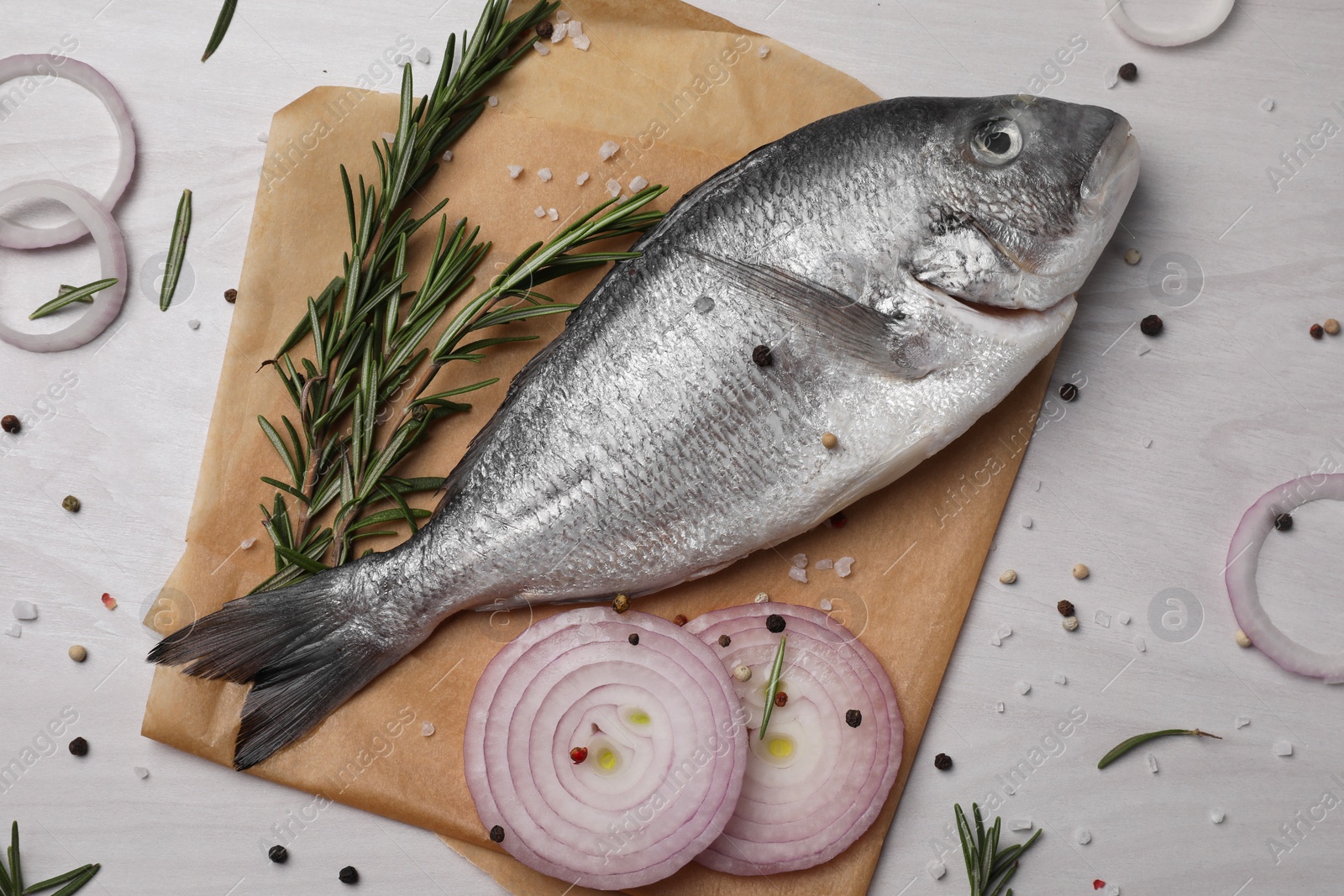 Photo of Raw dorado fish, spices and onion on white wooden table, flat lay