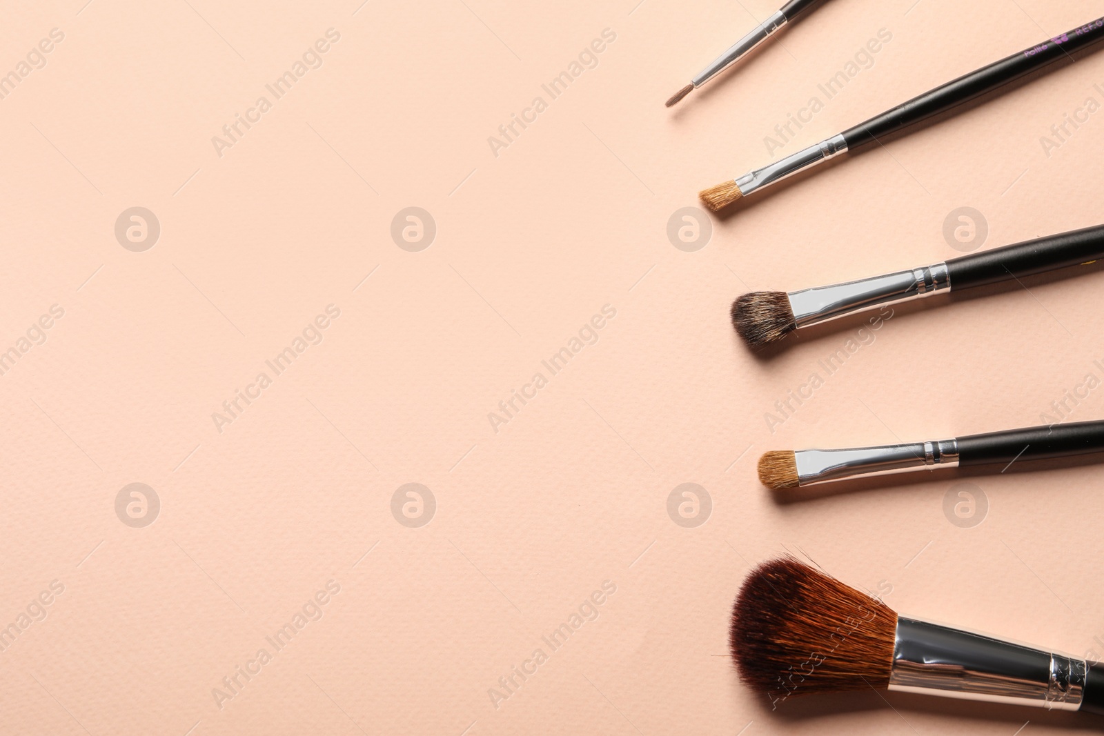 Photo of Different makeup brushes on light beige background, flat lay . Space for text