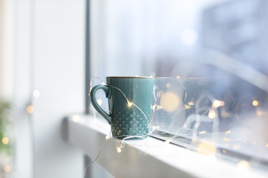 Cup of hot coffee near window indoors